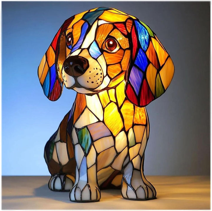 Siddende beagle-lampe med farvet mosaikglas-look i orange, hvid og blå, tændt mod blå baggrund og set forfra. 1