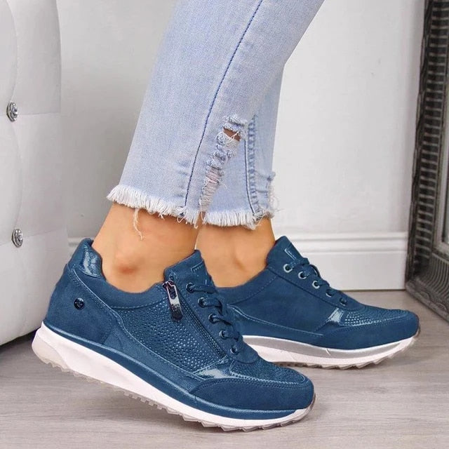 Model i lyse jeans bærer de samme sko i blå med lynlås på siden, snøring og hvid sål. 5