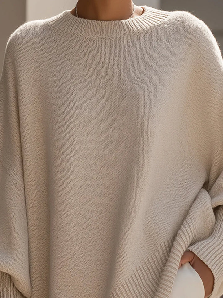 Nærbillede af beige strikbluse set forfra med ribstrikket rundhals og ribkant forneden. 2