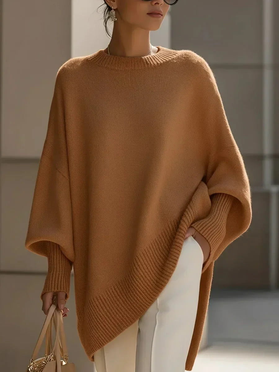Model i kamelbrun oversize strikbluse med ribkant og ribstrikkede ærmeopslag, hvide bukser og taske. 12