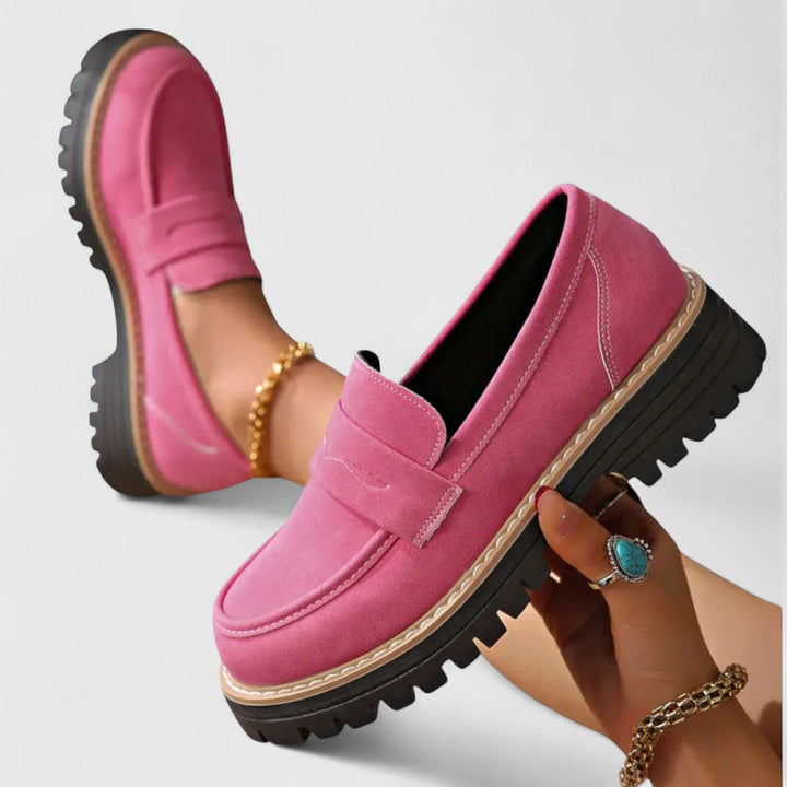 Pink loafers med tyk riflet sål, den ene holdt i hånden, den anden båret 3
