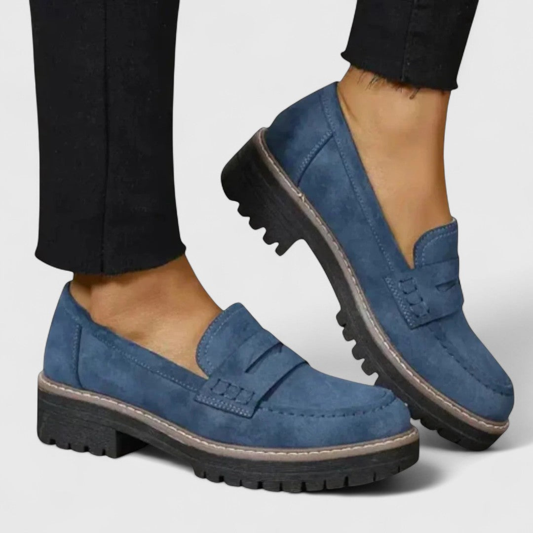 Blå ruskindslignende loafers med tyk riflet sål båret med sorte bukser, set fra siden 4