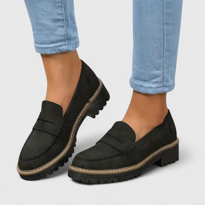 Sorte ruskindslignende loafers med kraftig riflet sål båret med lyse jeans, set skråt forfra 1