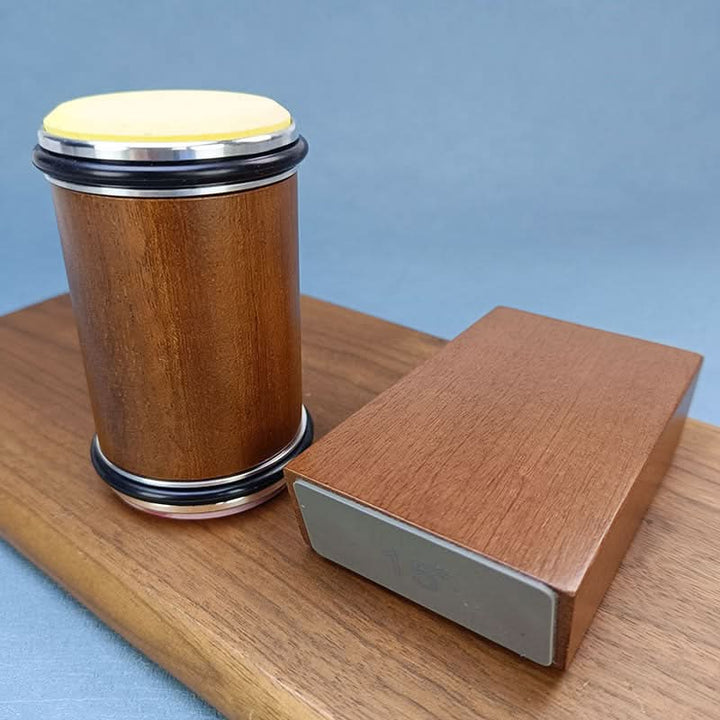 Slibecylinder i træ med gul slibeskive stående ved siden af vinkelblokken på et træbræt, mod blå baggrund. 5