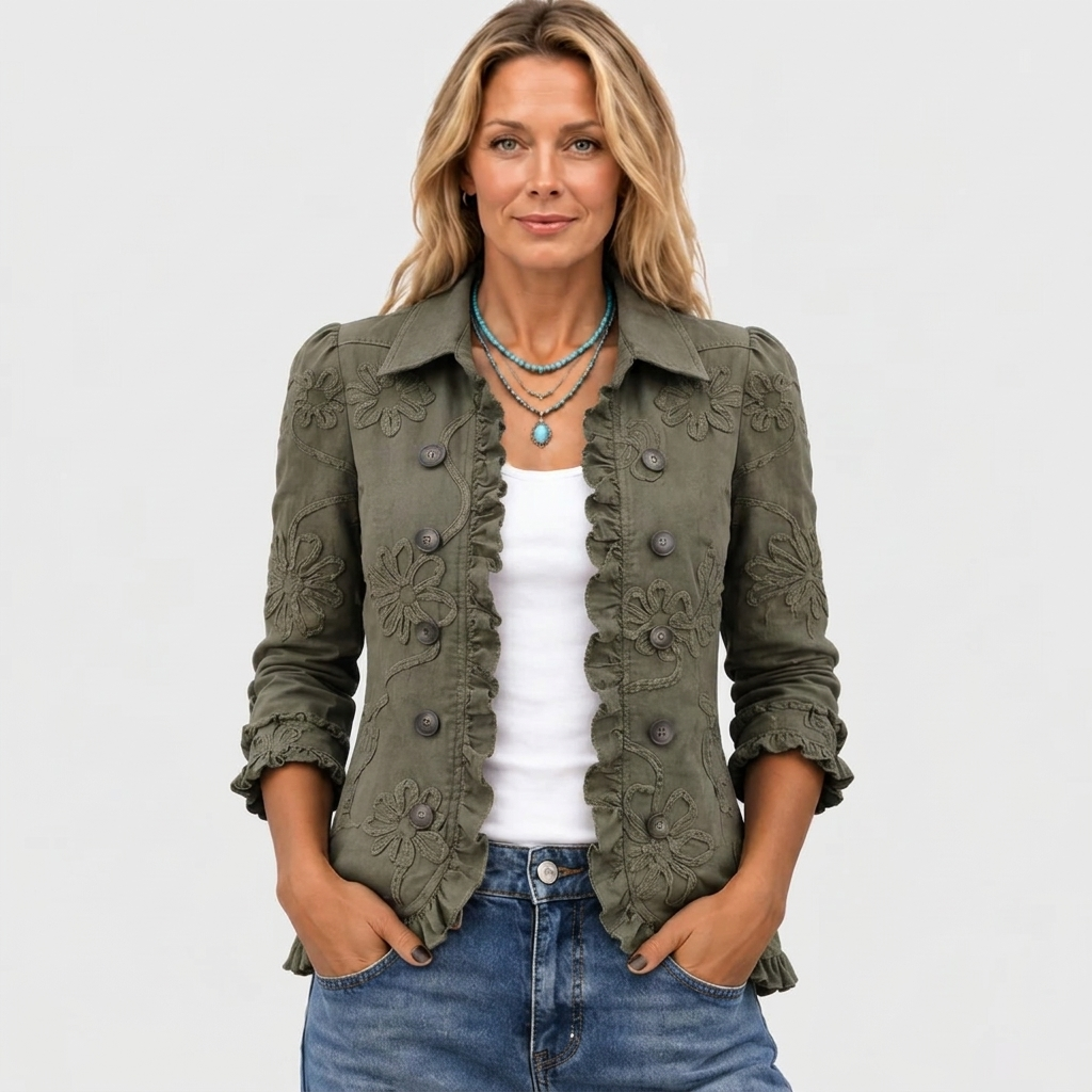 Modellen set forfra i den olivengrønne jakke med åben front, flæsekant og blomsterbroderi, båret med hvid top, turkis halskæde og jeans. 2