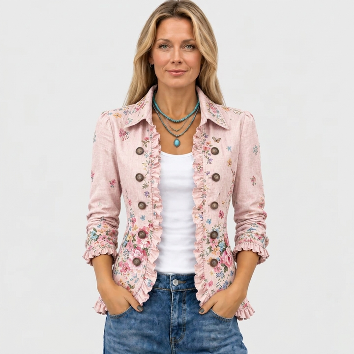 Model set forfra i den åbne lyserøde blomsterjakke med flæser og krave, stylet med hvid top, jeans og turkis halskæde. 2