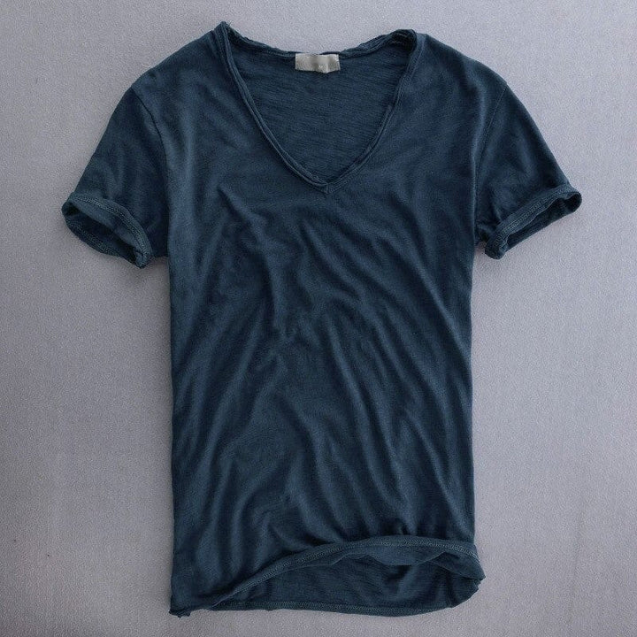 Mørkeblå kortærmet T-shirt med V-udskæring, lagt fladt på grå baggrund, med let struktureret stof og oprullet underkant. 5