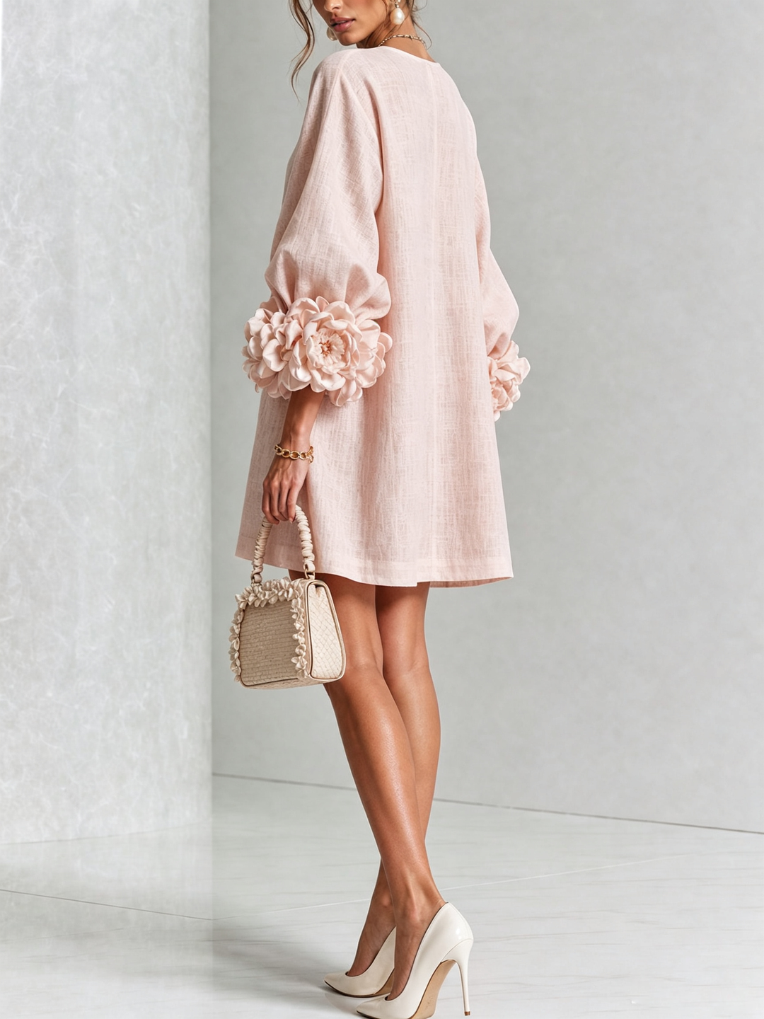 Model i lyserød minikjole set bagfra og lidt fra siden, med store rosmanchetter på ærmerne, hvid hæletaske og høje sko. 21