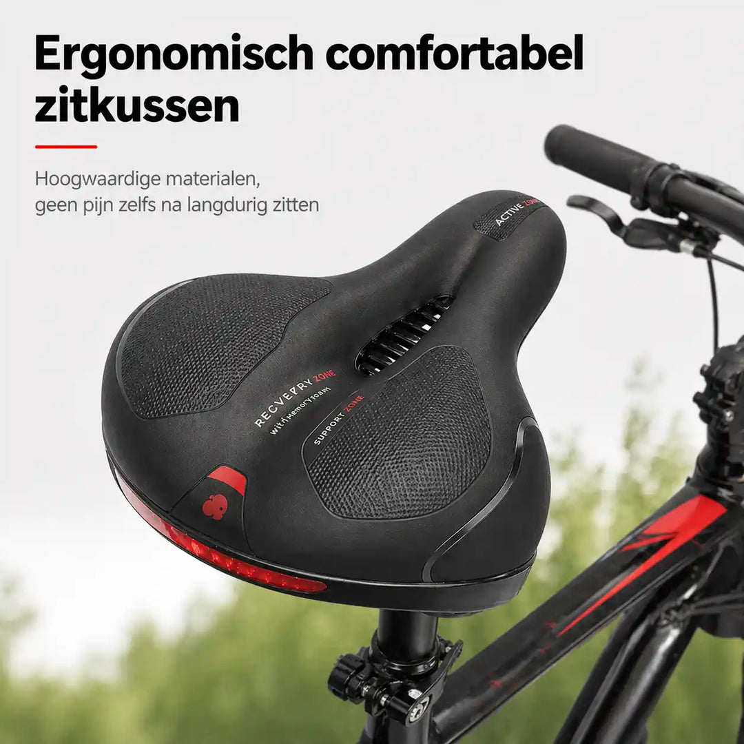 Sort cykelsadel med udskæring og rød reflekterende strip bagpå, monteret på en cykel med grønne træer i baggrunden. 1