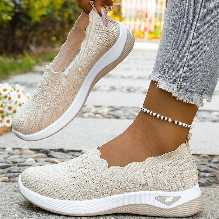 En beige sko holdes løftet, mens den anden bæres, så den indvendige bølgekant og sålen kan ses 9