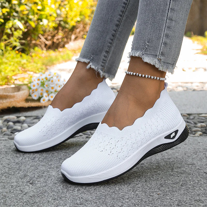 Hvide strikkede slip-on sko med bølget kant båret af model udendørs, med perlearmbånd om anklen 21