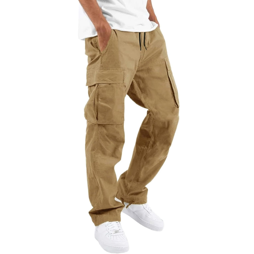 Model i kakifarvede cargobukser med store sidelommer og snøre i taljen, hvid T-shirt og hvide sneakers, set fra siden. 7