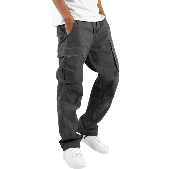Model i mørkegrå cargobukser med store sidelommer og snøre i taljen, hvid T-shirt og hvide sneakers, set fra siden. 8
