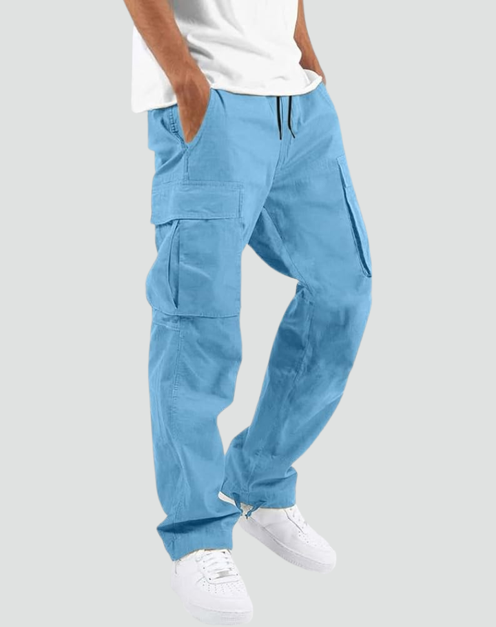 Model i lyseblå cargobukser med store sidelommer og snøre i taljen, hvid T-shirt og hvide sneakers, set fra siden. 14