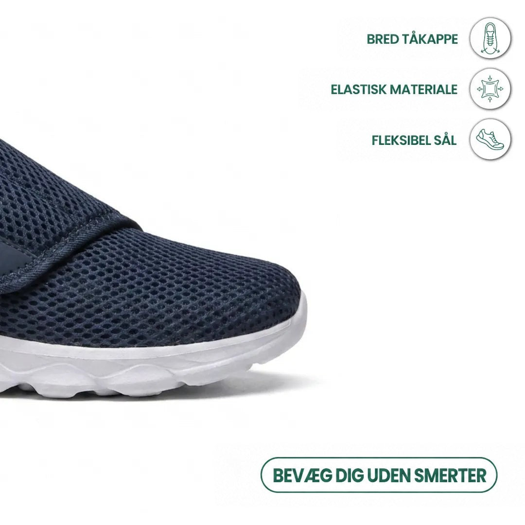 Nærbillede af den brede tåkappe på en marineblå mesh-sko med ikoner for bred tå, elastisk materiale og fleksibel sål. 5