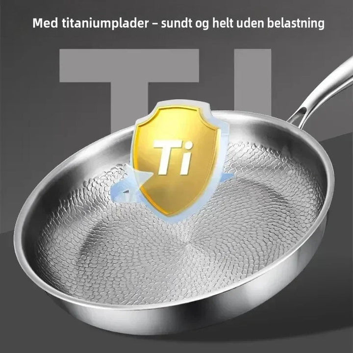 Pande med hamret bund og et gyldent skjoldsymbol over midten, der fremhæver titaniumlaget. 6