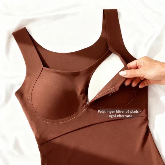 Brun tanktop lagt fladt på hvidt stof, hvor en hånd løfter stoffet og viser den indsyede bh-pude indeni. 6
