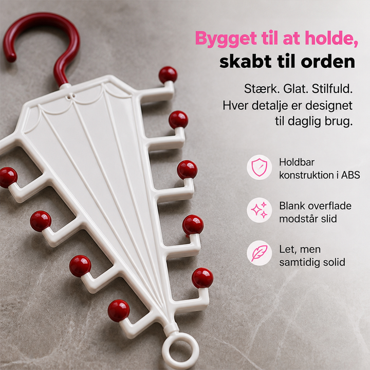 Nærbillede af hvid plastikbøjle med mørkerøde kugletips og krog, liggende på en marmoroverflade 3