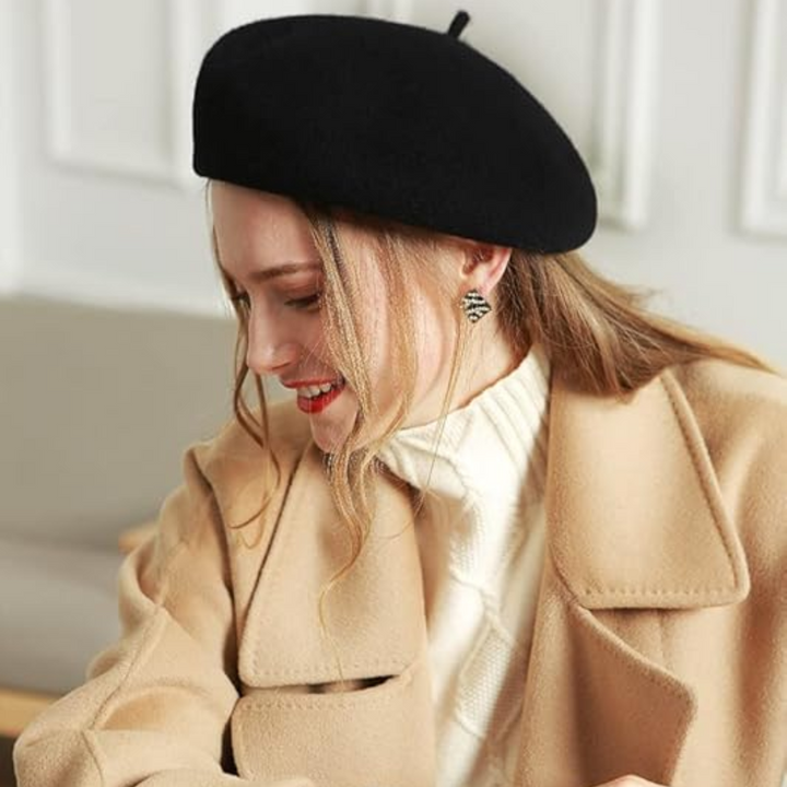 Sort baret båret af smilende kvinde i beige uldfrakke og hvid strikket rullekrave 22