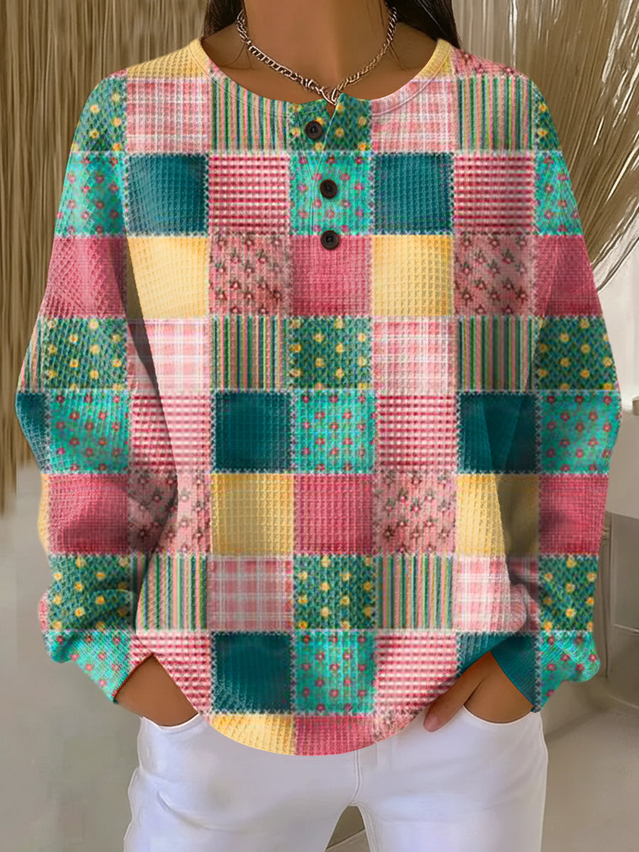 Vaffelstrikket trøje med patchwork-mønster i turkis, pink og gult med blomster og striber, vist på model. 20