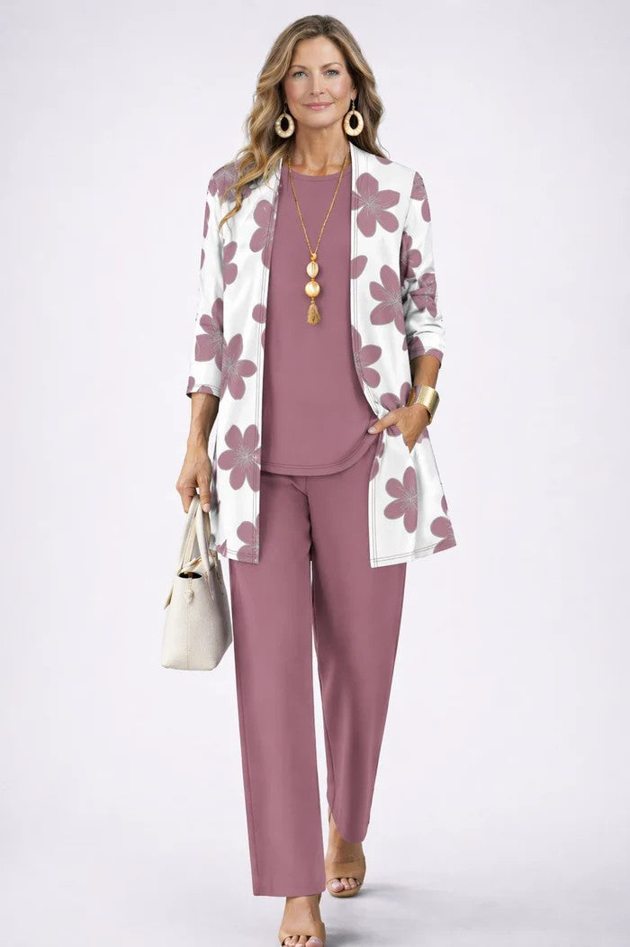 Model i hvid cardigan med store gammelrosa blomster over gammelrosa top og bukser, hånd i lommen. 18
