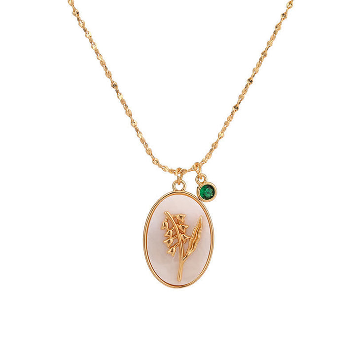 Goldene Halskette mit ovalem Anhänger, Blumenmotiv und grünem Edelstein, Schmuckaccessoire.