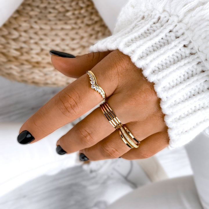Damenhand mit goldenen Ringen, Strickpullover, schwarzer Nagellack, eleganter Schmuck.