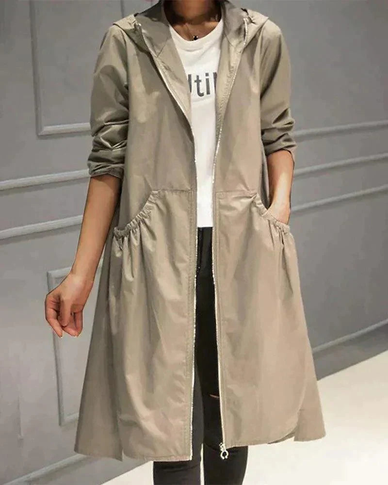 Beige regnfrakke båret åben over hvid t-shirt og sorte jeans, set forfra med hånd i lommen 2