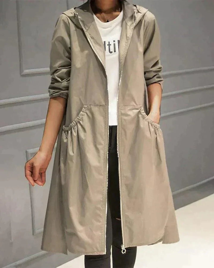 Beige regnfrakke båret åben over hvid t-shirt og sorte jeans, set forfra med hånd i lommen 2