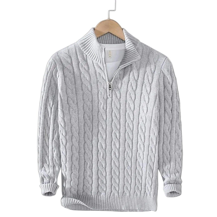 Lysegrå kabelstrikket trøje med halv rullekrave og kort metallynlås, hængende på en bøjle med hvid t-shirt under. 4