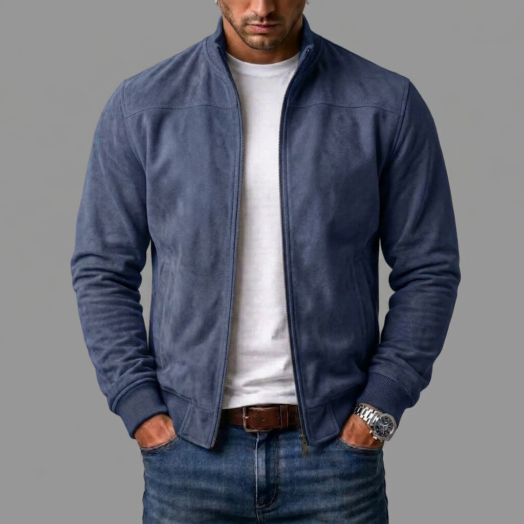 Model i dybblå jakke i ruskindslook med åben lynlås og ribmanchetter, båret over hvid t-shirt og jeans. 6
