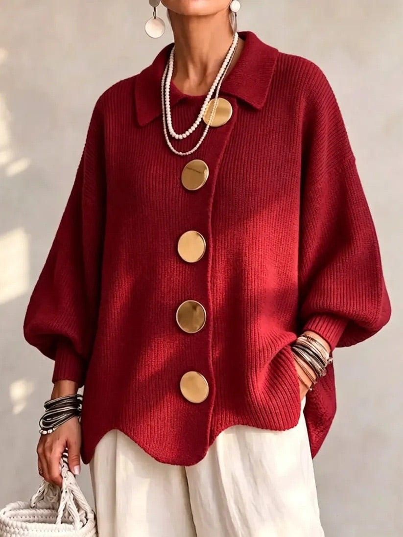 Model i rød ribstrikket cardigan med spids krave og store guldfarvede knapper, set forfra i naturligt lys. 11