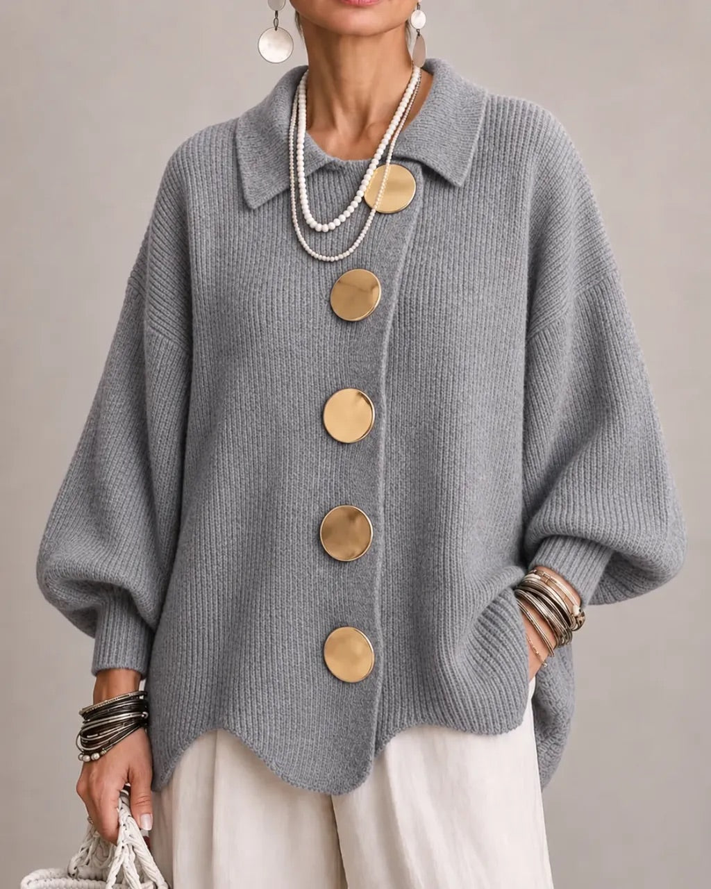Model i grå ribstrikket cardigan med store guldfarvede knapper, spids krave og brede ærmer, set forfra. 18