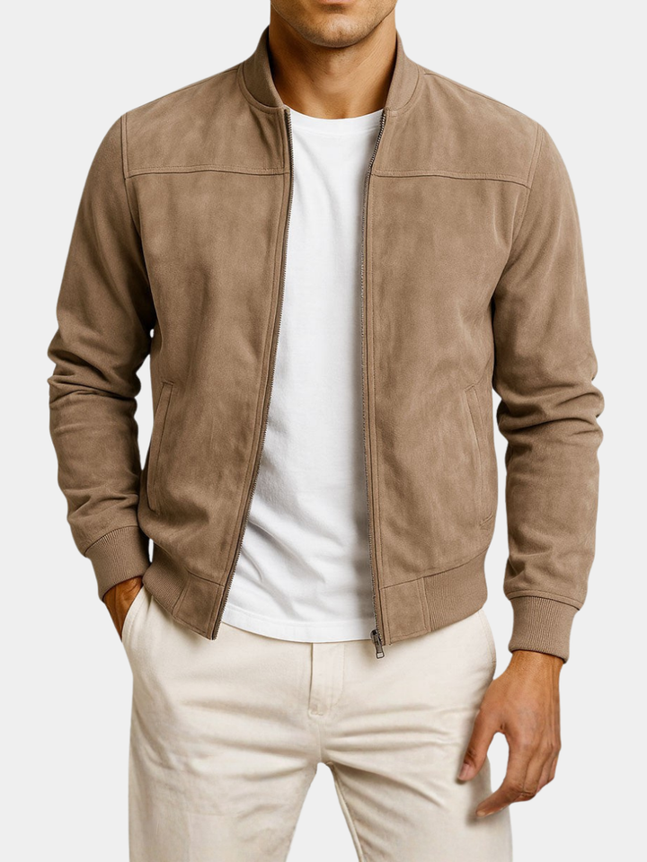 Model i beige jakke med åben lynlås, set fra lidt længere væk mod hvid baggrund, med hvid t-shirt og lyse bukser. 6