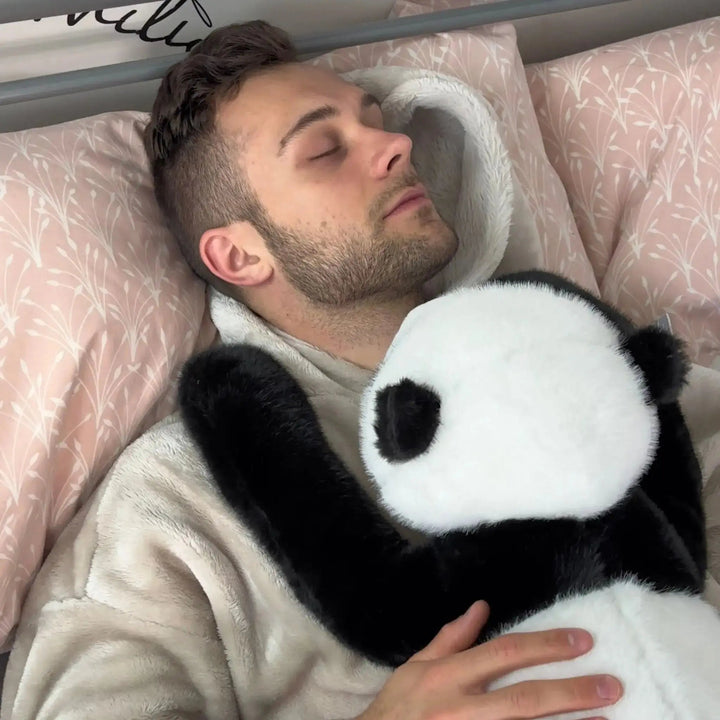 Sovende mand i sengen holder panda-krammedyret ind til brystet med de lange sorte arme hvilende over hans skulder. 11