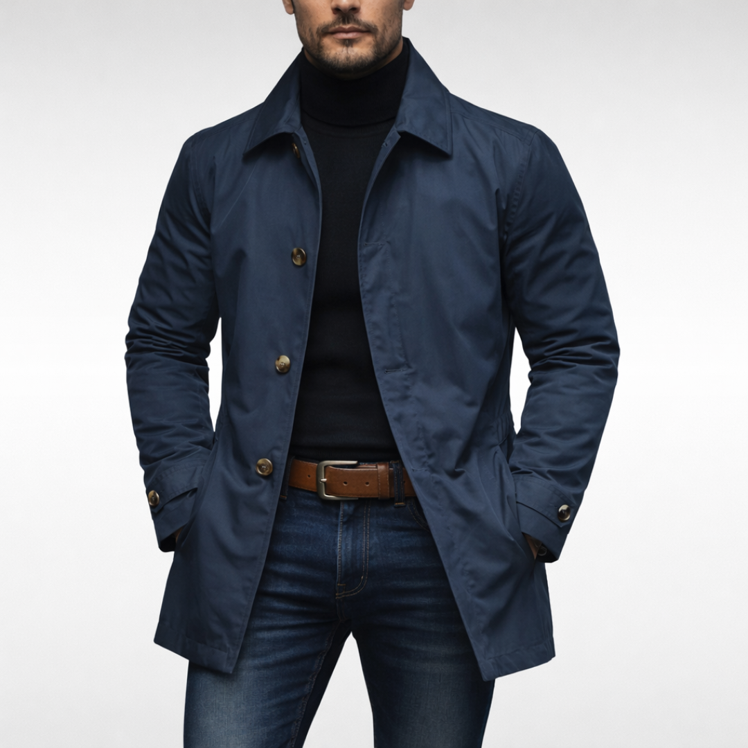 Marineblå udgave af frakken båret af model med sort rullekravetrøje, jeans og brunt bælte; knapperne er lysere. 3