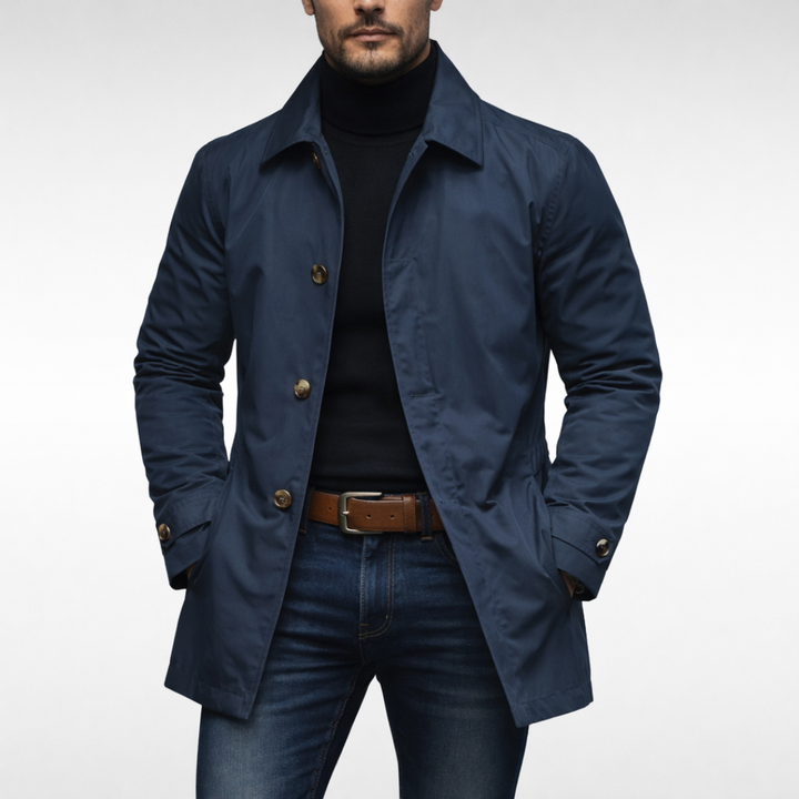 Marineblå udgave af frakken båret af model med sort rullekravetrøje, jeans og brunt bælte; knapperne er lysere. 3