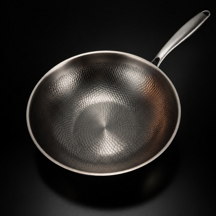 Wokken set ovenfra, så det hamrede mønster i hele den tomme pande og det lange håndtag tydeligt ses. 2