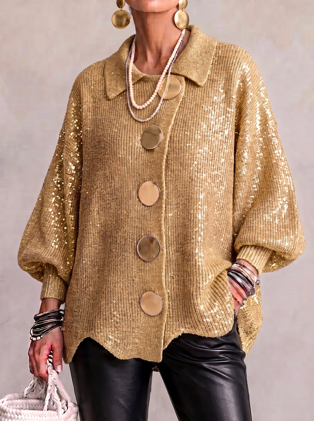 Model i guldfarvet cardigan med glitrende pailletter, store runde knapper og sorte læderbukser, set forfra. 3