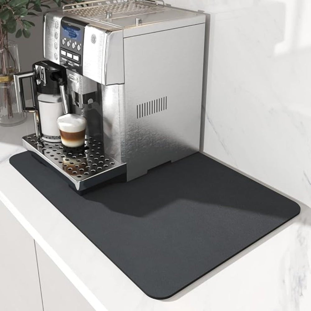 Mørkegrå måtte under en espressomaskine med en latte i glas, placeret på en hvid marmorbordplade. 2