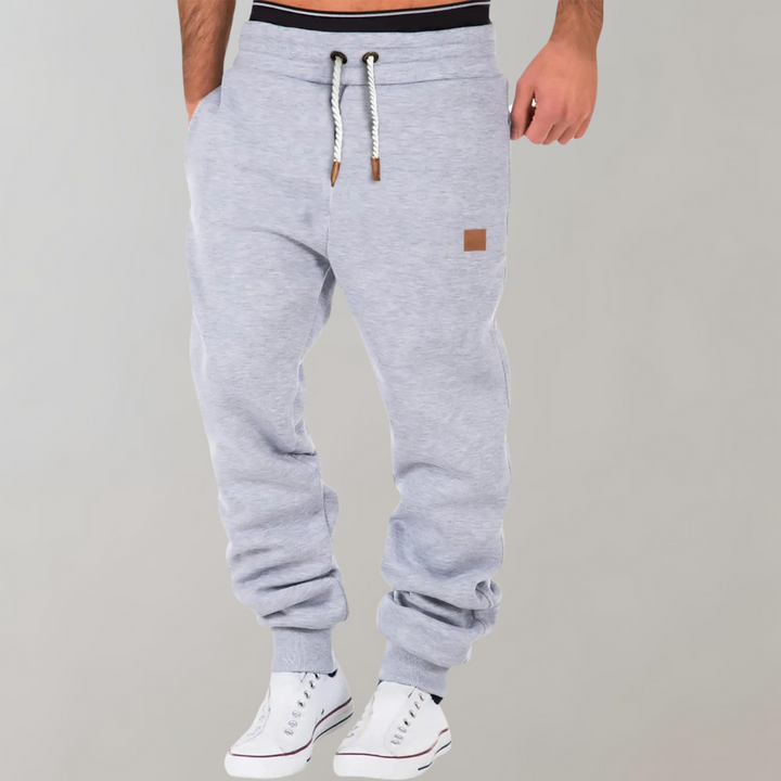 Model i lysegrå joggingbukser med hvidt snøre og lille læderlabel, set forfra 4